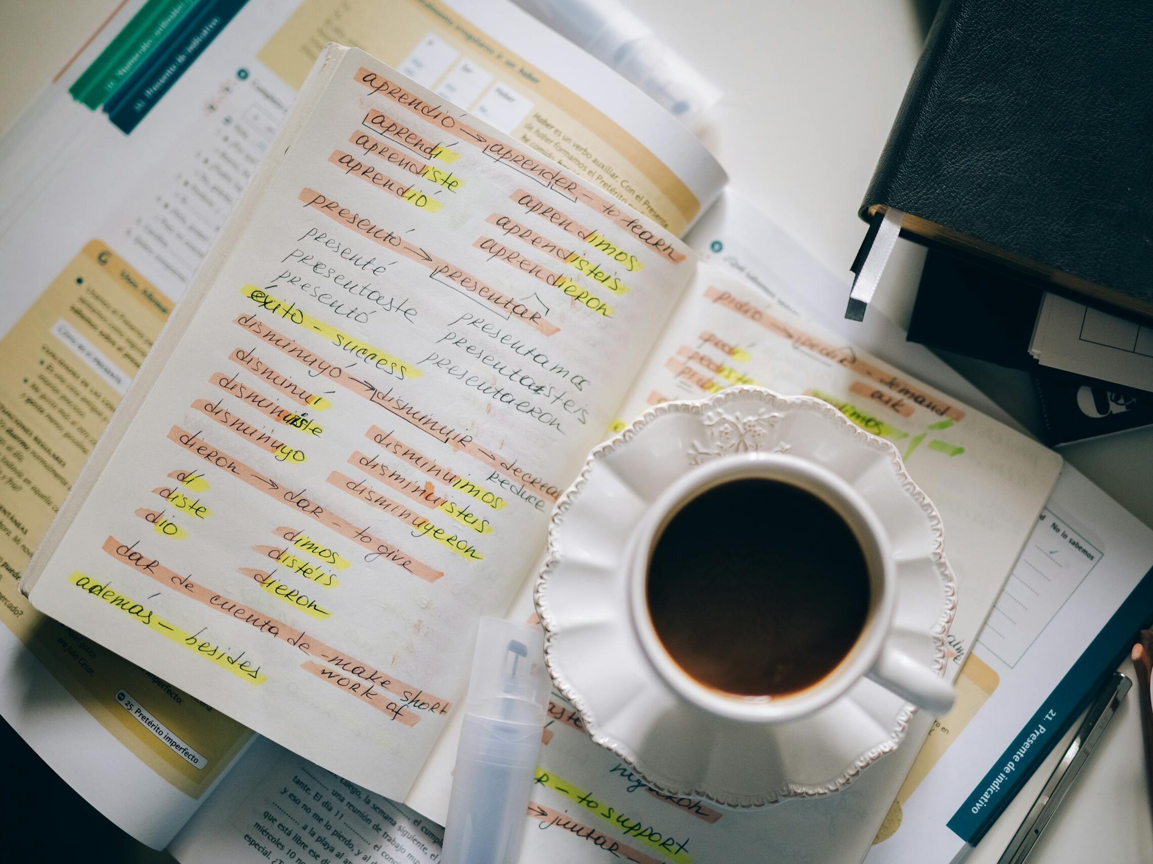 A cup of coffee on handwritten Spanish notes for language learning inspiration.